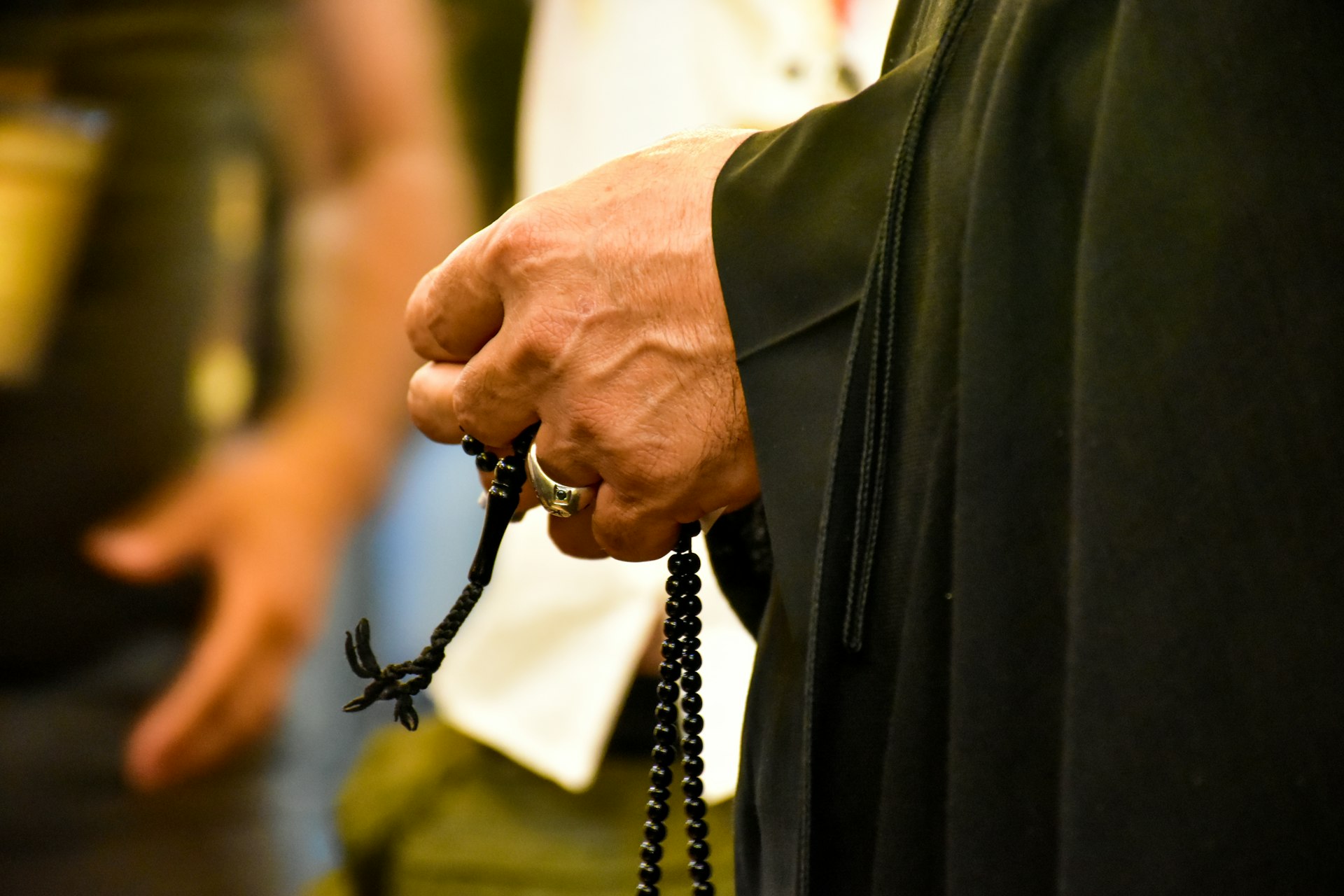 person in black coat wearing black leather sling bag